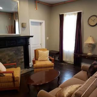 A cozy living room with a fireplace, armchairs, and a sofa.