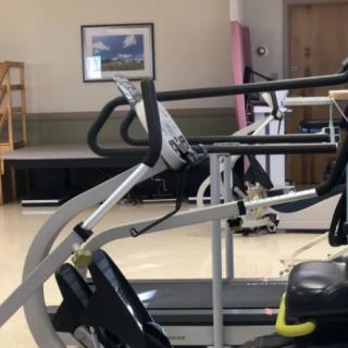 A gym with exercise equipment, including a treadmill, in an indoor setting.