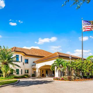 A sunny day view of a residential building with palm trees and an American flag.
