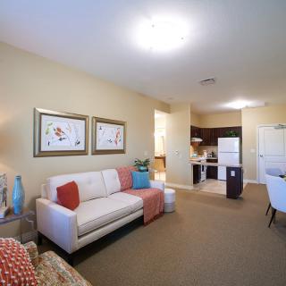 A cozy living room with an open-concept kitchen, featuring a sofa, modern decor, and wall artwork.