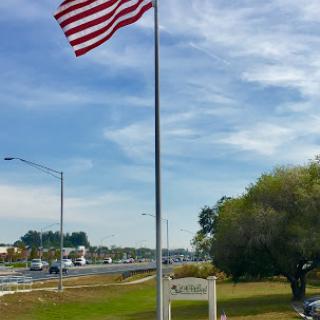 An American flag waving proudly on a flagpole beside a serene landscape.
