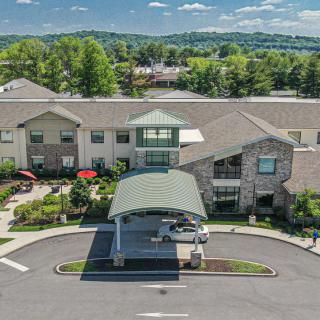 An aerial view of a modern building with a landscaped entrance and parking area.