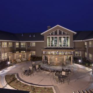A well-lit building with an inviting courtyard featuring outdoor seating, captured at night.