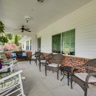 A cozy porch with wicker chairs, a table, and a ceiling fan, perfect for relaxing outdoors.