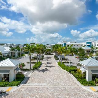 A luxurious tropical resort with palm-lined pathways under a partly cloudy sky.