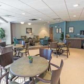 A cozy lounge area with tables and chairs, featuring neutral colors and decorative plants.