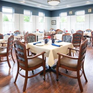 An elegant dining room with neatly arranged tables and chairs, illuminated by natural light.