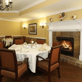A cozy dining room with a fireplace, elegantly set table, and comfortable chairs.