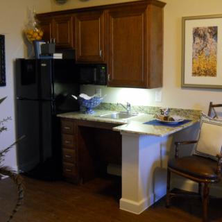 A small kitchen area with a refrigerator, microwave, and wooden cabinets over a countertop.