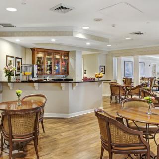 A cozy cafe interior with a bar counter, wooden tables, and chairs.