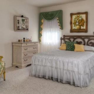 A vintage-style bedroom with white bedding and decorative pillows, featuring a dresser and wall art.