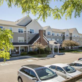 A residential apartment complex with cars parked in front on a sunny day.