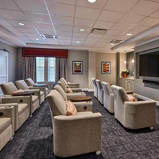 A modern home theater room with multiple recliner chairs facing a large projection screen.