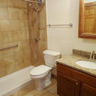 A clean and modern bathroom with a shower, toilet, sink, and mirror.