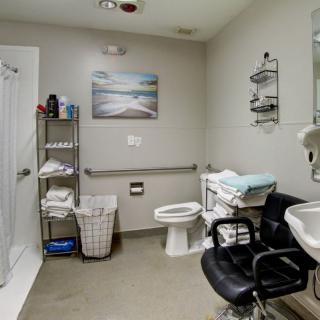 A modern bathroom equipped with a shower, sink, toilet, and storage shelves.