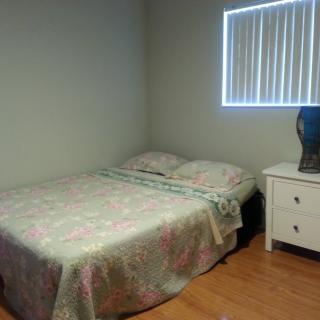 A simple bedroom with a bed and a nightstand next to a window.
