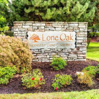 A landscaped entrance with a brick sign displaying 'Lone Oak'.