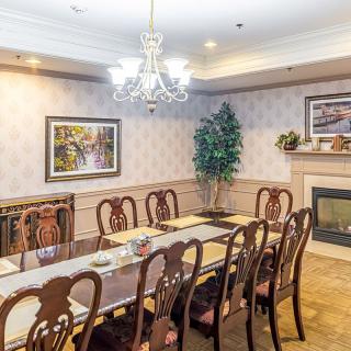 A traditional dining room with a long table, elegant chairs, and a chandelier.