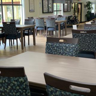A spacious dining area with multiple tables and chairs, featuring a bright and inviting atmosphere.