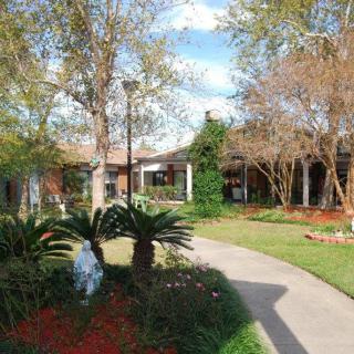 A scenic garden with a pathway leading to a building surrounded by trees and greenery.
