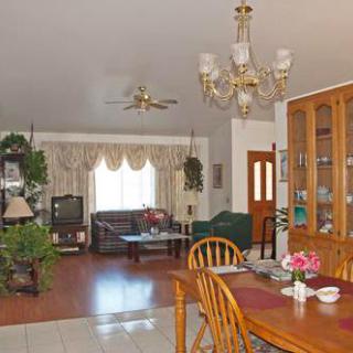 A cozy living and dining area with wooden furniture, decorative plants, and a chandelier.