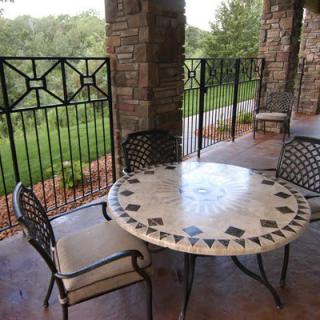 A cozy outdoor patio with a decorative table and chairs overlooking a scenic landscape.