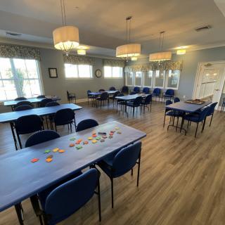 An empty classroom with arranged tables and chairs, illuminated by overhead lights.