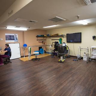 A spacious therapy room equipped with exercise materials and seating arrangements for rehabilitation activities.