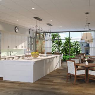 A modern kitchen with an open dining area, featuring white cabinetry and ample natural light.
