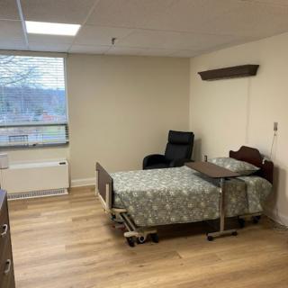 A simple hospital room with a bed, chair, and window.