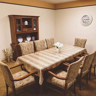A cozy dining room with a large table surrounded by chairs, featuring a wooden cabinet and decorative elements.