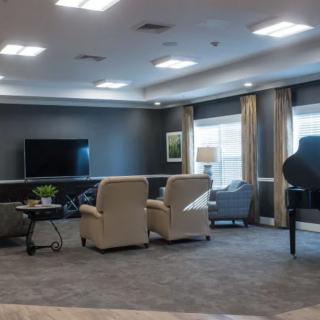 A spacious living room with comfortable seating, a television, and a grand piano.