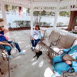 A group of people relaxing and conversing in a gazebo, accompanied by a small dog.