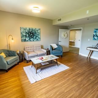 A modern living room with stylish furniture and art, featuring a sofa, armchair, coffee table, and wooden flooring.