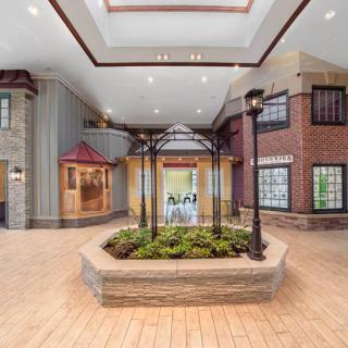 A spacious atrium with architectural details, featuring a central plant display and illuminated by a skylight.
