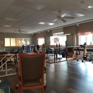 A spacious rehabilitation therapy room equipped with various exercise machines and a comfortable chair.