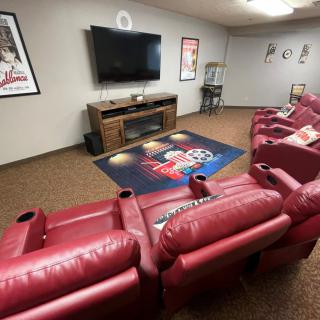 A cozy home theater featuring red recliners, a large TV, and movie-themed decor.