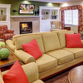 A cozy living room with a beige sofa, red cushions, and a fireplace.