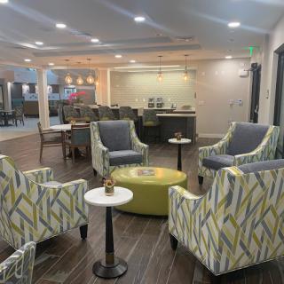 A modern lobby area featuring comfortable armchairs and small tables, with soft lighting creating an inviting atmosphere.