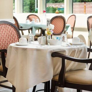 An elegantly set dining table in a restaurant with white tablecloths and comfortable chairs.