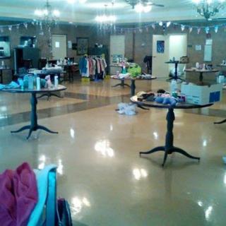 A room set up for a sale event with tables displaying various items including clothing and household goods.