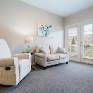 A cozy living room featuring a comfortable sofa and armchair, complemented by a side lamp and artwork on the wall.