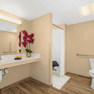 A modern bathroom with a sink, mirror, and toilet, featuring decorative flowers.