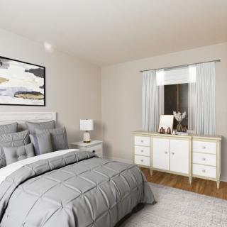 A modern bedroom with gray bedding, a bedside lamp, and a white dresser under a window.