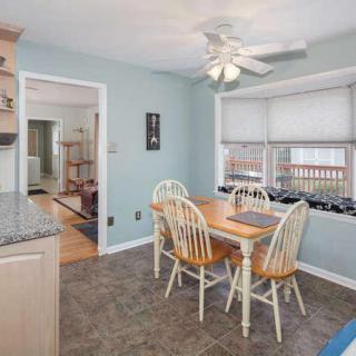 A cozy kitchen dining area with a wooden table and chairs, ceiling fan, and window blinds.