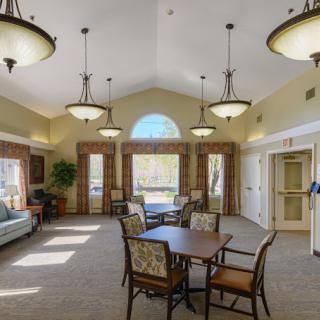 A spacious lounge area with tables, chairs, and elegant lighting fixtures.
