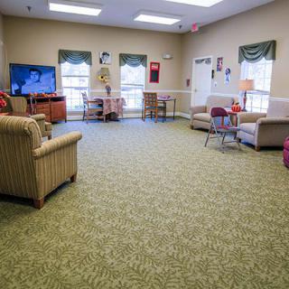 A cozy living room with comfortable seating, a carpeted floor, and a television.