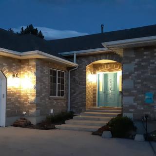 A well-lit house entrance at night with brick exterior and a front porch.