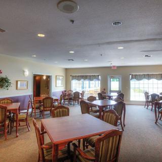 A spacious dining area with multiple tables and chairs, illuminated by natural light from large windows.