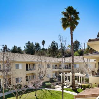 A sunny view of an apartment complex with a central courtyard and palm trees.